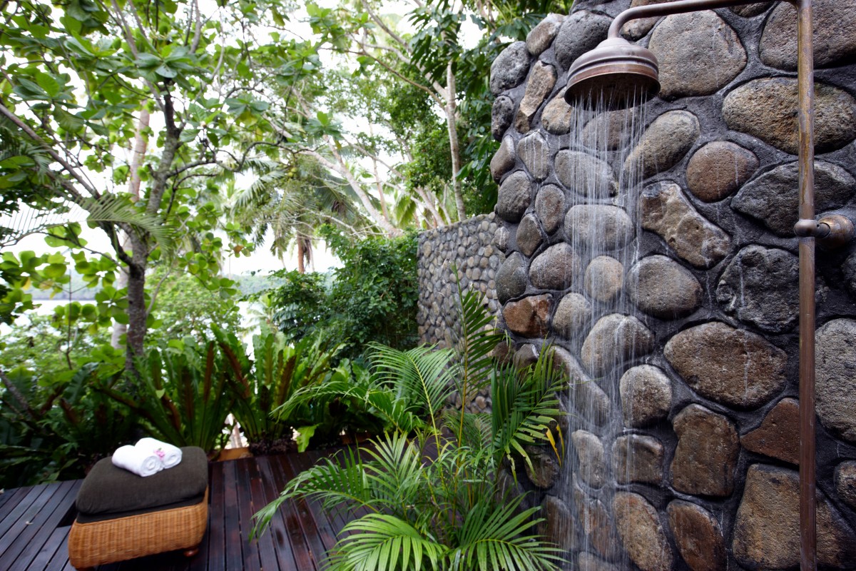 Natural Outdoor Bathroom Design with Natural Stone Wall and Wood Deck.